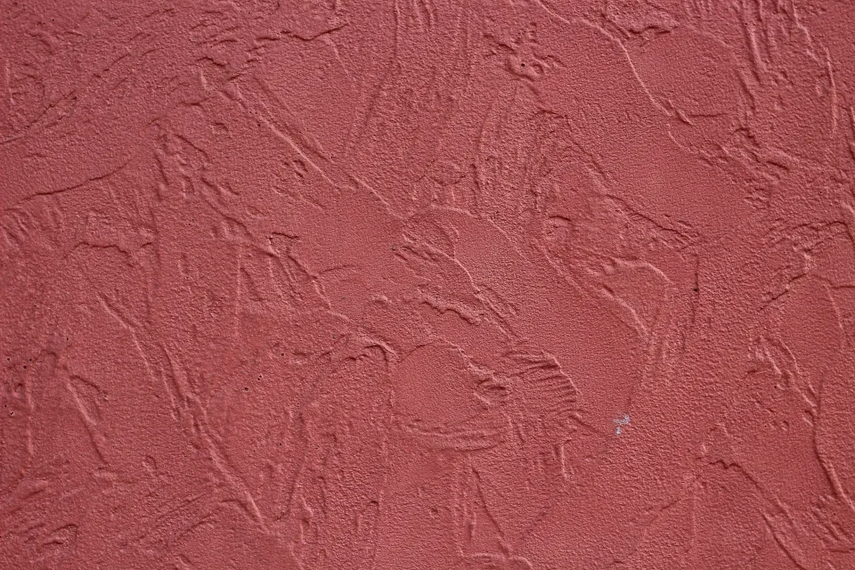 Pared exterior con parches de masilla y preparación de superficie antes de pintar, junto a un deck de madera