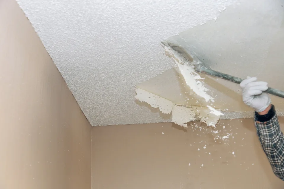 Cocina con techo liso pintado, luces empotradas y lámparas colgantes sobre isla verde
