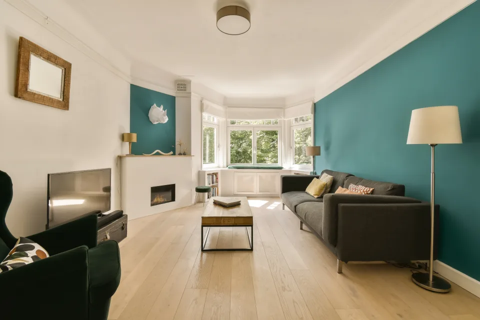 Interior de cocina amplia recién pintada con gabinetes color crema, isla verde y piso de madera oscura